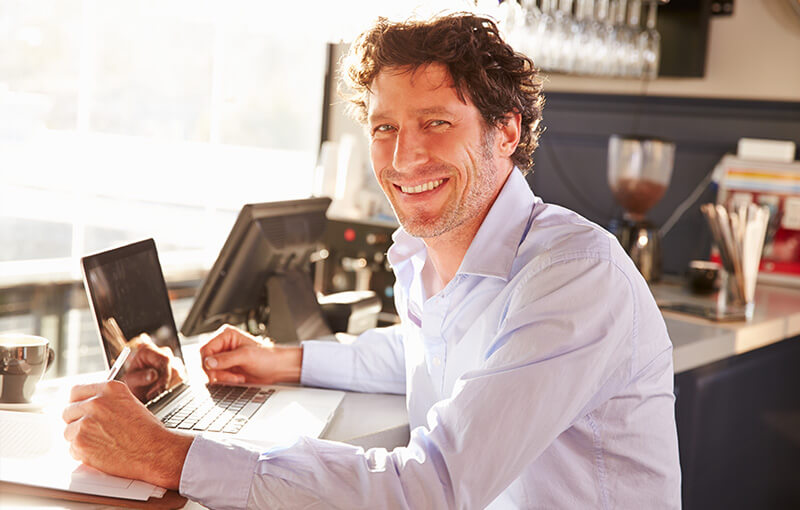 happy restaurant owner using apple laptop