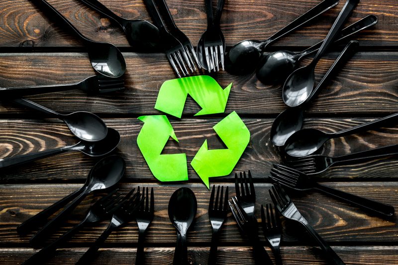 recycling and eco concept with plastic spoons and forks frame on wooden background top view